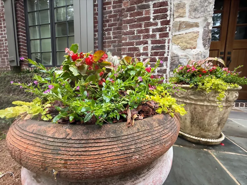 Stone urn planters filled with seasonal color at a front entry